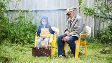 老爷爷和他的小孙子坐在院子里的火边<strong>取暖</strong>